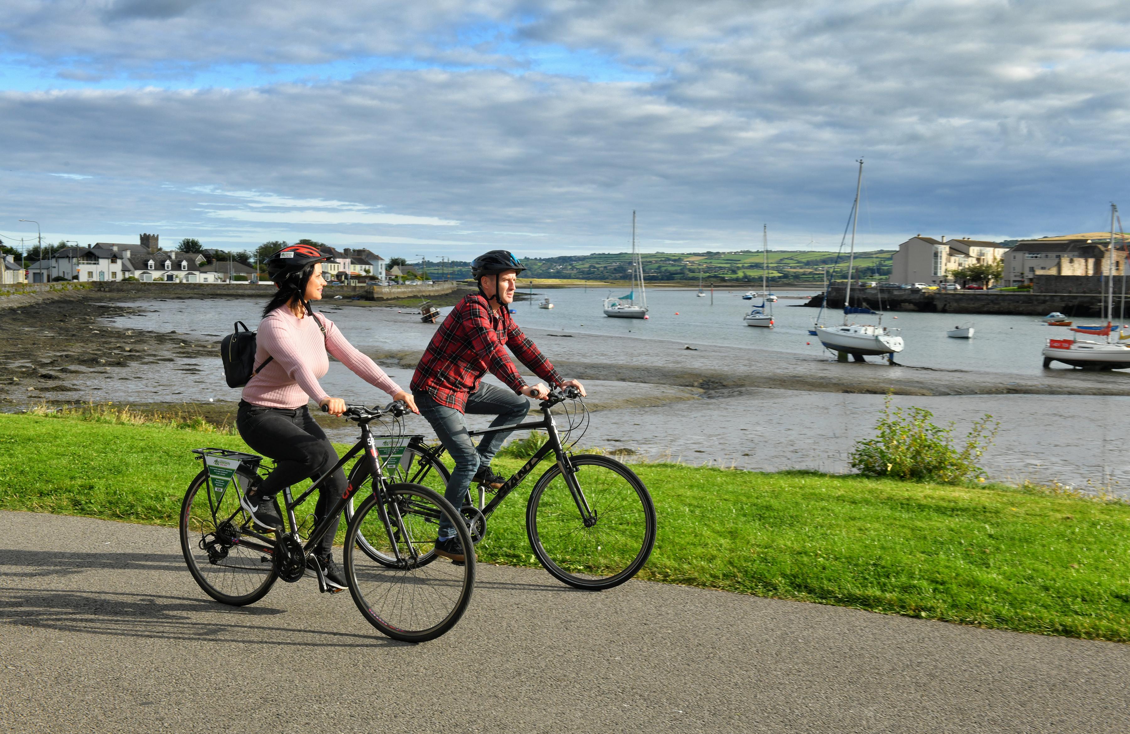 Photo of two people cycling by the sea